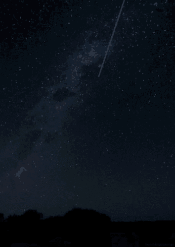 a shooting star is visible in the night sky above a mountain
