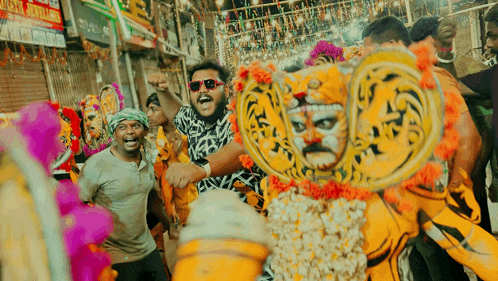 a man wearing sunglasses and a mask is surrounded by people in a crowd .