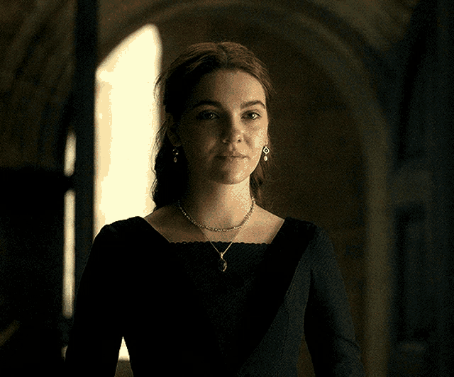 a woman in a black dress with a necklace and earrings