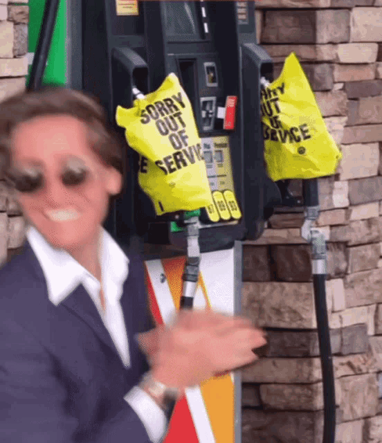 a man stands in front of a gas pump with a bag that says sorry out of service