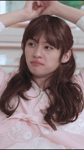 a woman in a pink dress with pearls on the collar is making a funny face