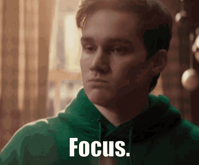 a man in a green hoodie has the word focus written on his face