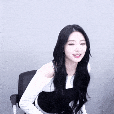 a woman with long black hair is wearing a white top