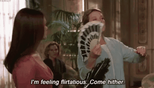 a woman is holding a fan in her mouth and saying `` i 'm feeling flirtatious . come hither . ''