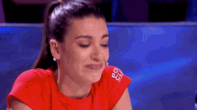 a woman wearing a red shirt with the word club on the sleeve is smiling