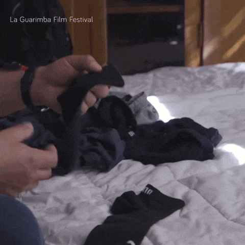 a person is folding clothes on a bed and the words la guarimba film festival are on the bottom right