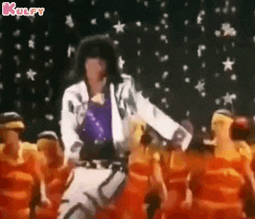 a man in a white jacket is dancing on a stage with a group of people .
