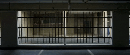 the inside of a building with a prison cell behind a fence