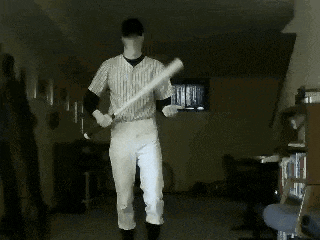 a man in a baseball uniform is standing in a dark room holding a bat