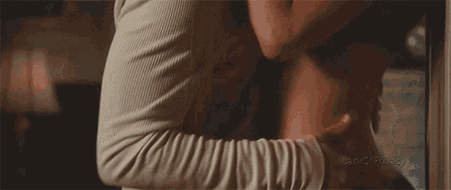 a woman in a black bra is hugging a man on a bed