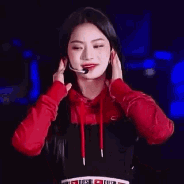 a woman in a red hoodie is standing in front of a microphone and applauding .