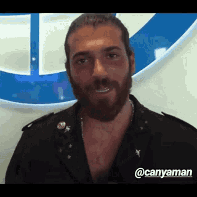 a man with a beard is standing in front of a blue and white sign .