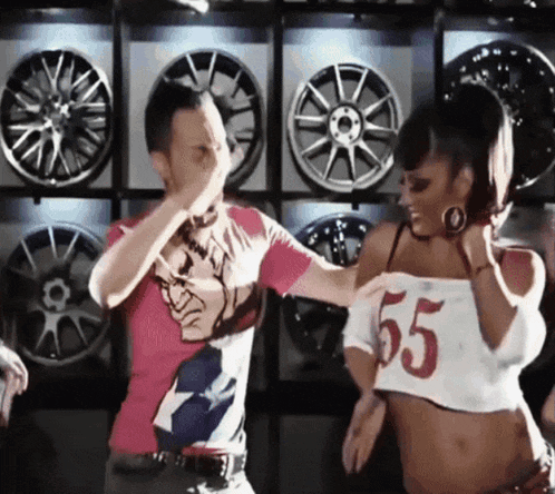 a man and a woman are dancing in front of a wall of wheels