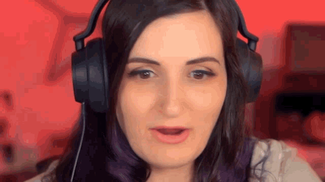 a woman with purple hair is wearing headphones and making a funny face .