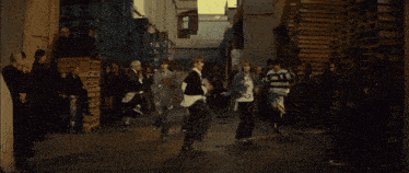 a group of young men are dancing in an alleyway and one of them is wearing a sweatshirt that says ' a '