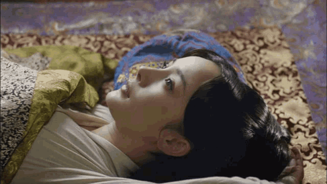a woman is laying on a bed with a blanket