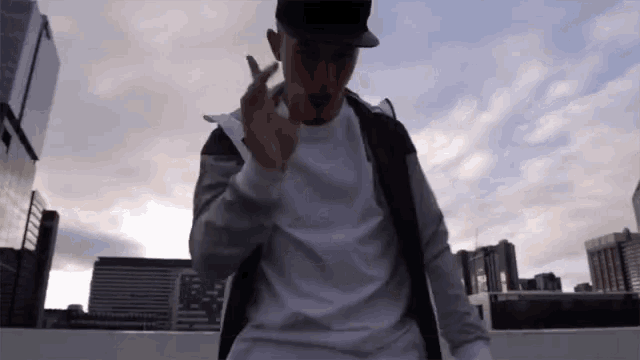 a man wearing a white shirt and a black hat is giving the ok sign