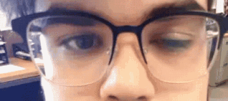 a close up of a person wearing glasses looking at the camera .