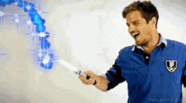 a man in a blue shirt holds a light saber