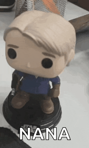 a funko pop of a man with a sword is sitting on a table .
