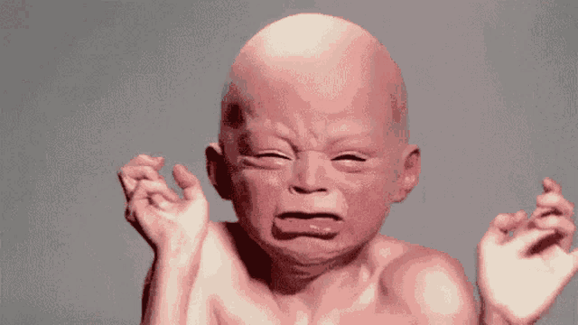a bald baby is crying with his eyes closed and his mouth open
