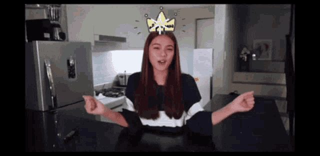a woman with a crown on her head stands in a kitchen