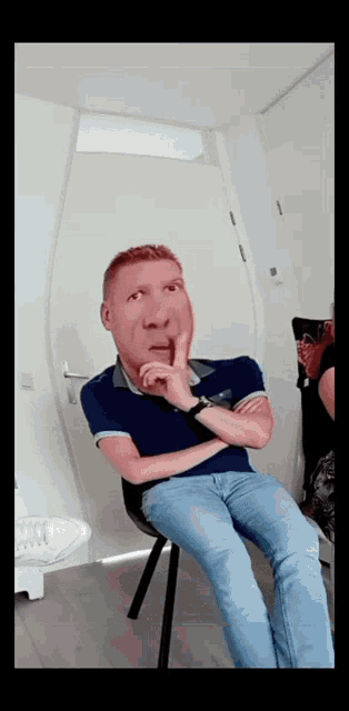 a man is sitting in a chair with his hand on his chin and a fake face on his face
