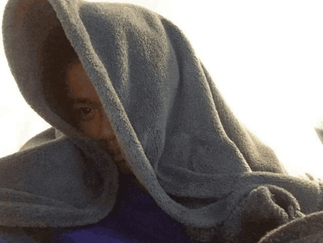 a person wrapped in a blue blanket with their eyes visible