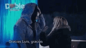 a man in a hooded jacket is standing next to a woman and says gracias luis gracias .