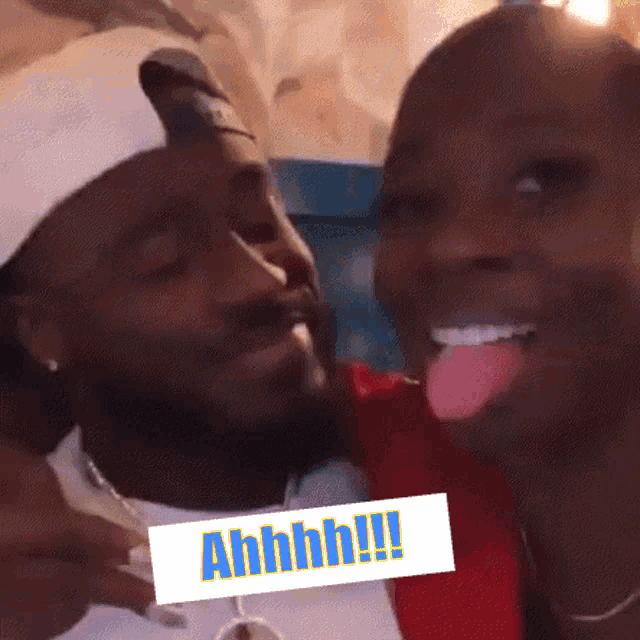 a woman sticking her tongue out next to a man with a sign that says ahhhh on it