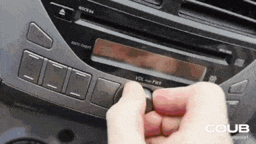 a person pressing a button on a car radio that says volume push pwr