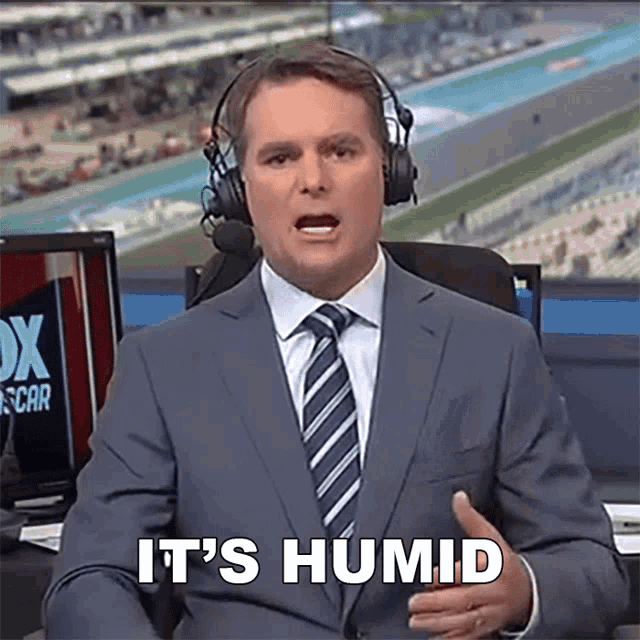 a man in a suit and tie says it 's humid while wearing headphones