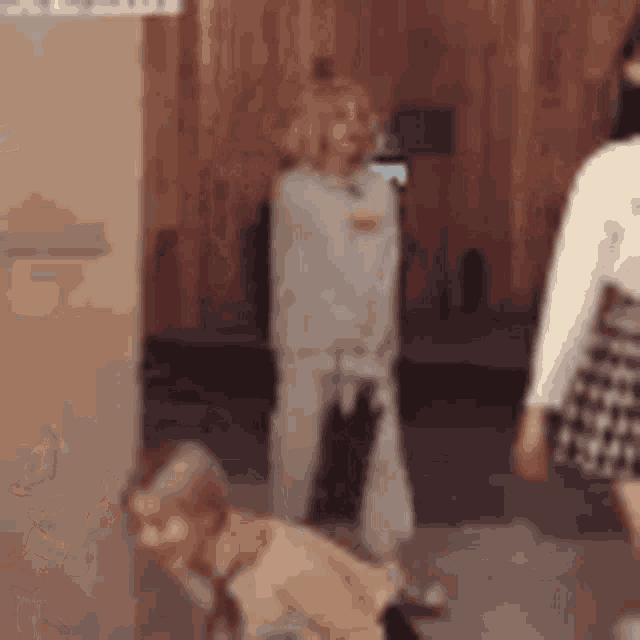 a woman and a child are standing next to each other in a room in front of a wooden wall .