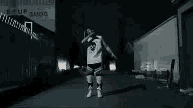 a man is standing in a dark alleyway at night .