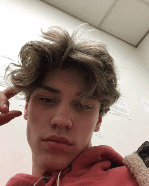 a young man wearing a red hoodie is making a peace sign