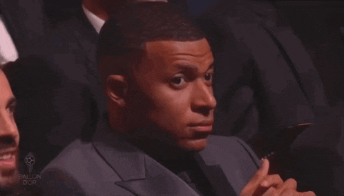 a man in a suit and tie is sitting in a crowd with the word ballon on the bottom