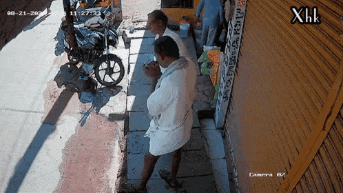 a motorcycle is parked on the side of the road next to a man and a sign that says xhk