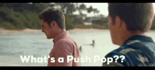 two men are standing next to each other on a beach and one of them is asking what 's a push pop ?