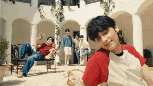a group of young men are standing in a courtyard with one laying on a bench