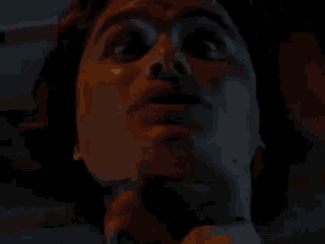 a close up of a man with a beard making a funny face in a dark room .