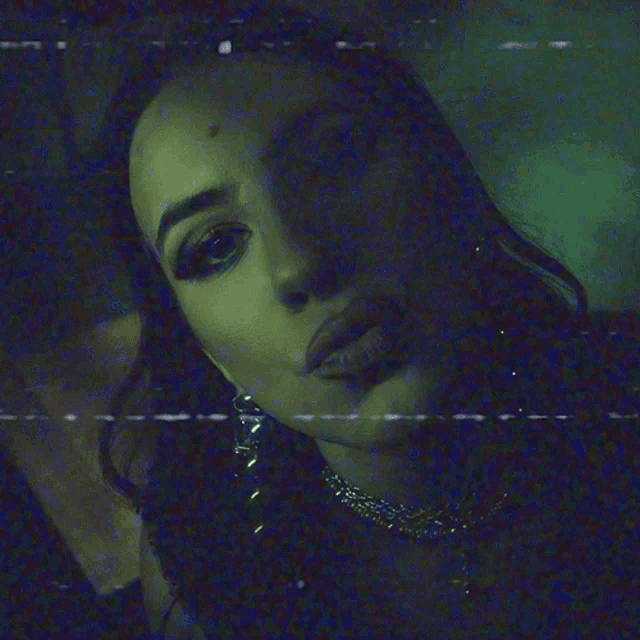 a close up of a woman 's face in a dark room with a blue background