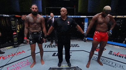 a referee stands between two fighters in a ring that says ufc