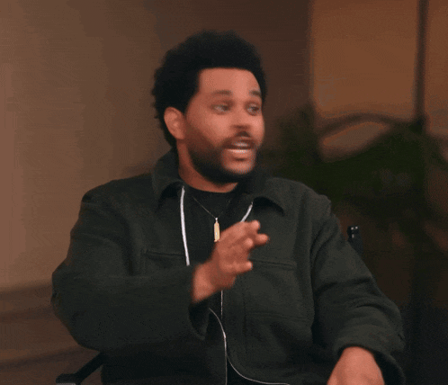 a man with a beard is wearing headphones and pointing his finger