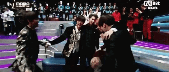 a group of people are hugging each other on a stage in front of a mnet logo