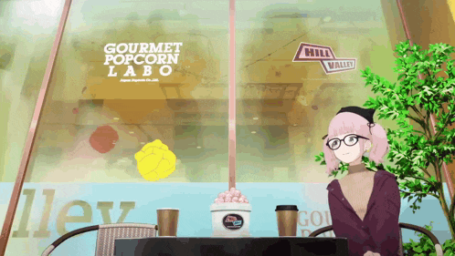 a girl sits at a table in front of a gourmet popcorn lab