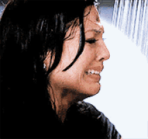 a woman is crying while taking a shower in front of a waterfall