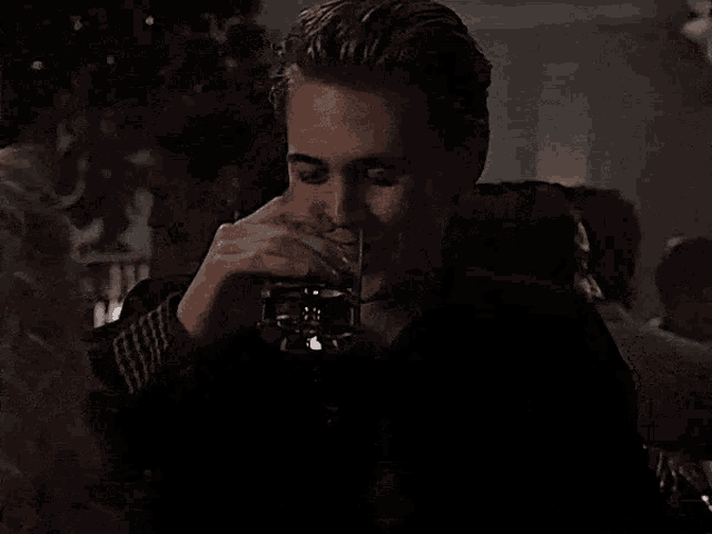 a man is drinking a glass of beer from a can .