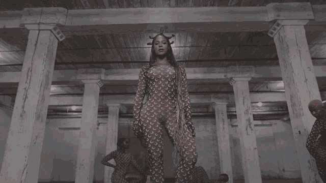 a woman in a jumpsuit stands in a room with columns