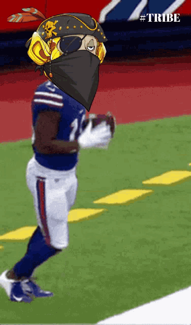 a football player wearing a mask and sunglasses is running on a field with #tribe written on the bottom