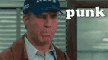 a man wearing a blue hat and a brown jacket is standing in front of a window with the word punk written on it .